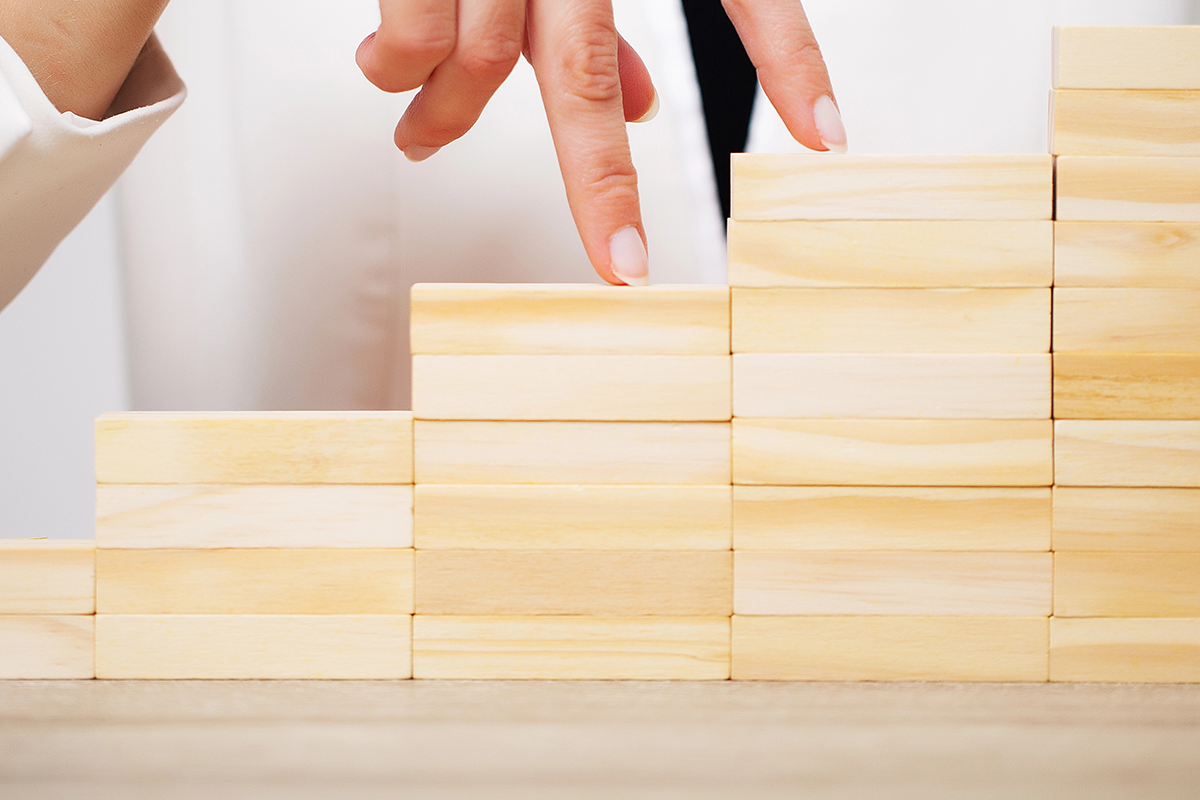 Trayectoria profesional representada por subir una escalera de bloques de madera.